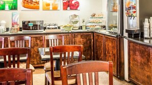 Un bar pour le petit-déjeuner avec des tabourets en bois, une machine à café et un réfrigérateur équipé d’un distributeur de jus.