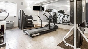 Une salle de sport équipée d’un tapis de course, d’un vélo d’appartement et d’appareils de musculation.