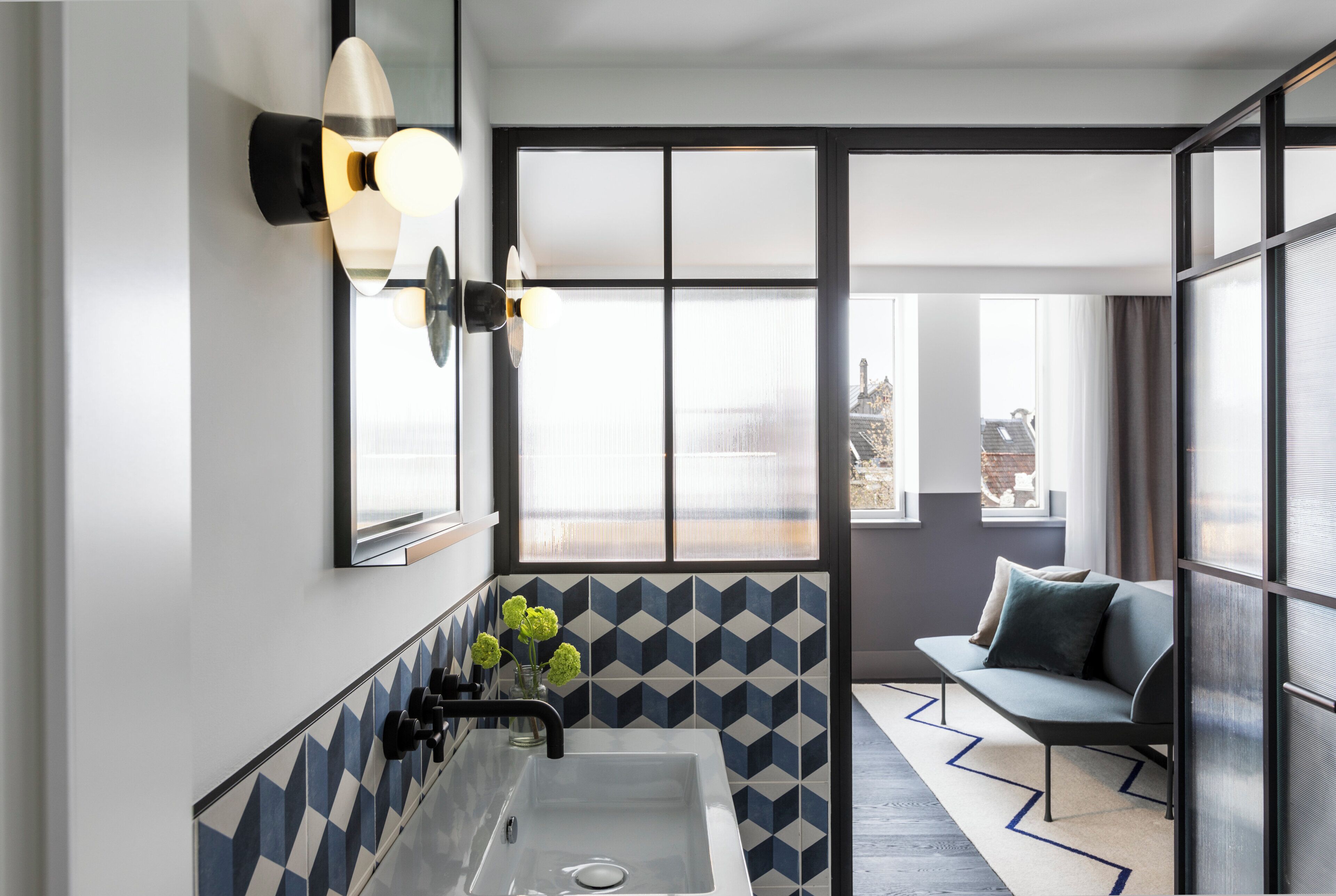 A modern bathroom with a large sink, a mirror, and a window with a view of the city.