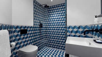Ein Badezimmer mit geometrischem Fliesenmuster, einem weißen Waschbecken und einer Toilette.