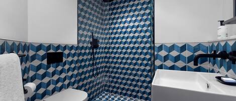 A bathroom with a geometric tile pattern, a white sink, and a toilet.