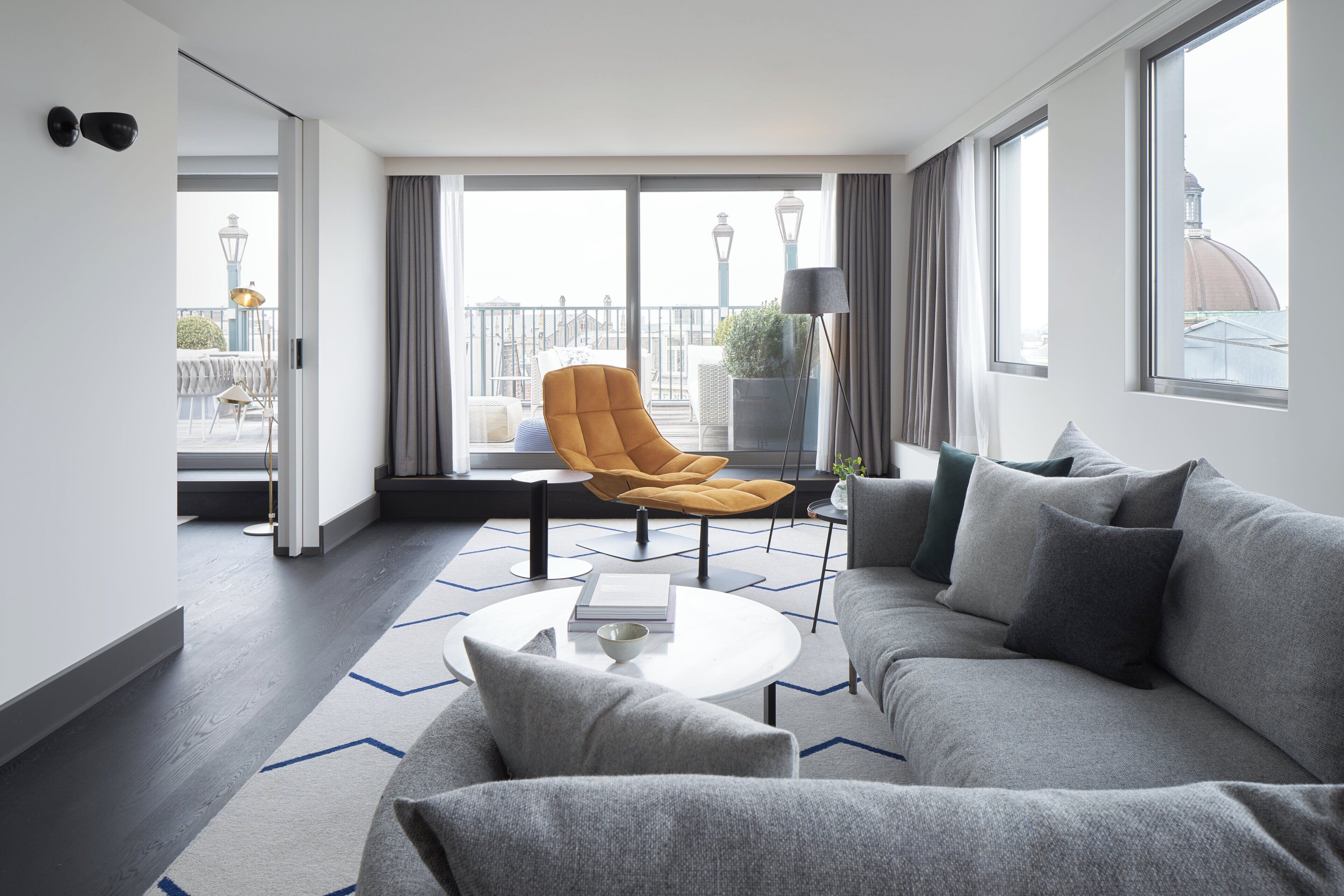 Un salon moderne avec un canapé gris, un fauteuil jaune et une table basse.