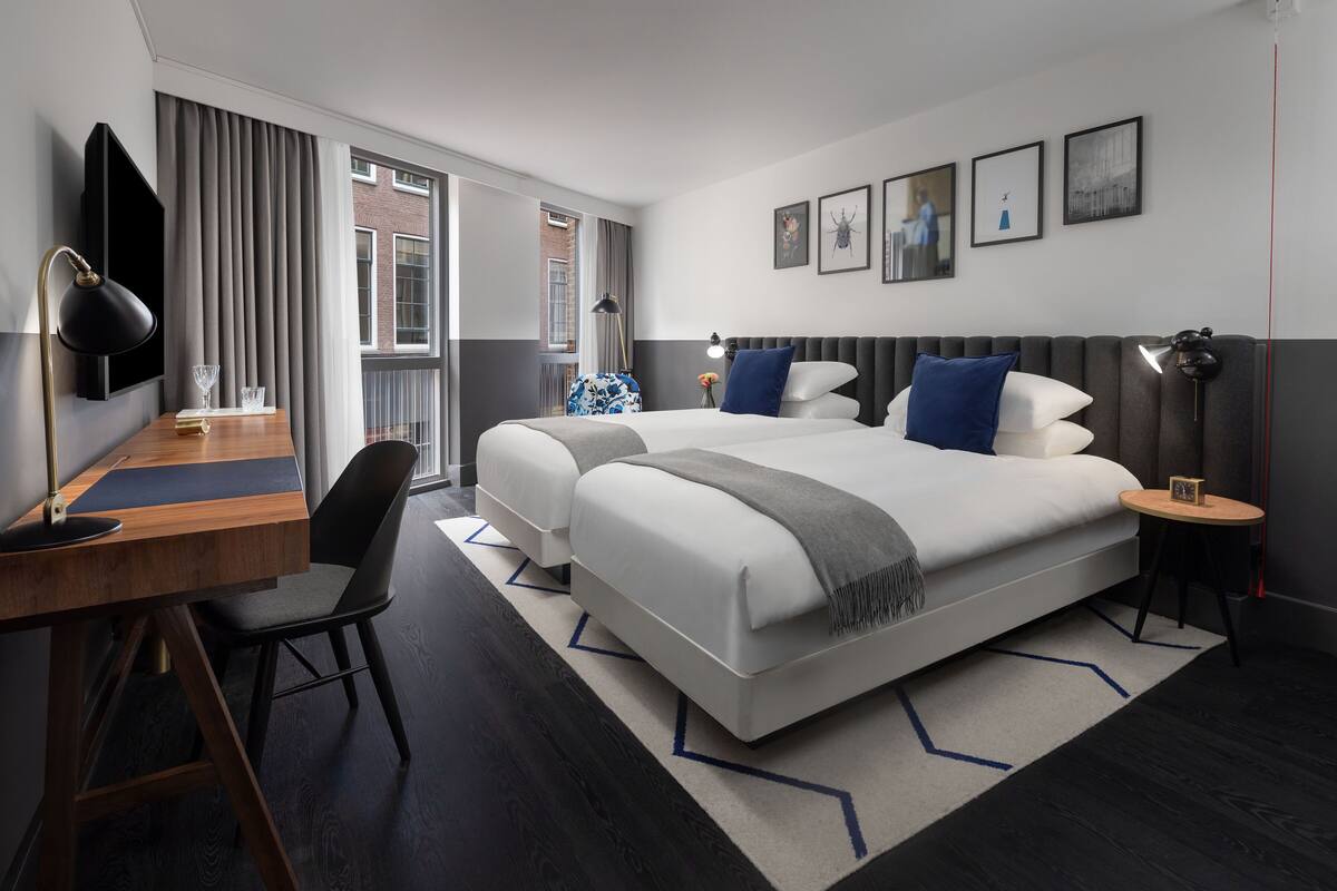 Ein modernes Hotelzimmer mit einem großen Bett, einem Schreibtisch und Blick auf die Stadt.