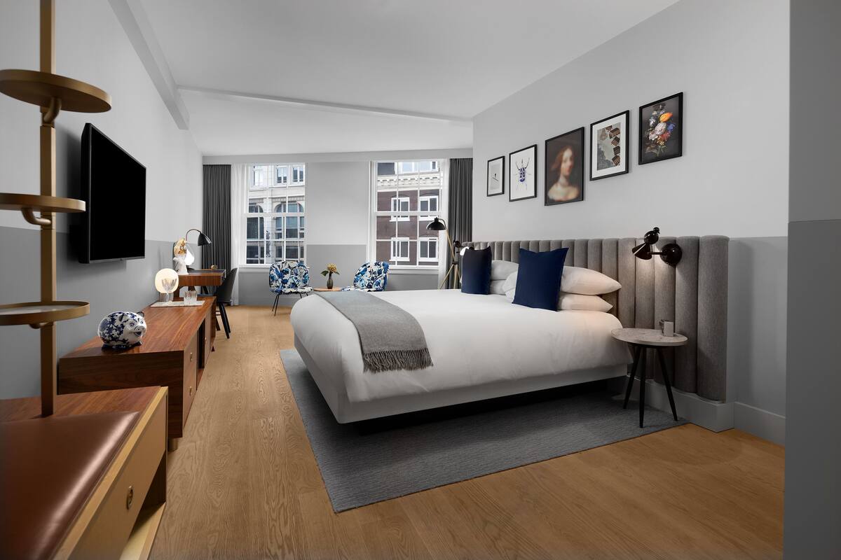 Ein modernes Schlafzimmer mit einem großen Bett, einem Schreibtisch, einem Stuhl und einem Fernseher.