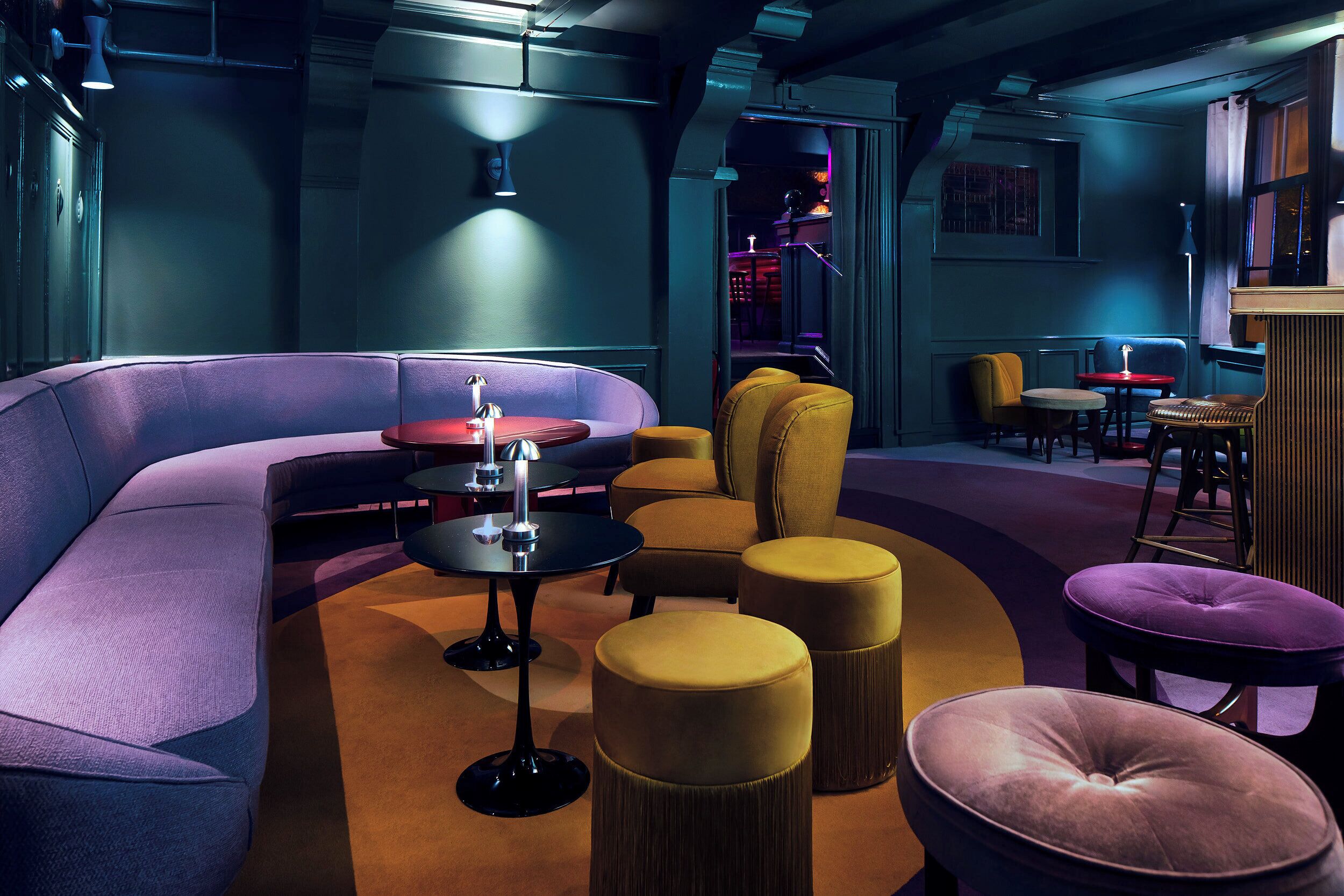 A modern lounge area with a curved sofa, round tables, and ottomans.