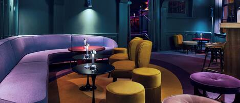 A modern lounge area with a curved sofa, round tables, and ottomans.