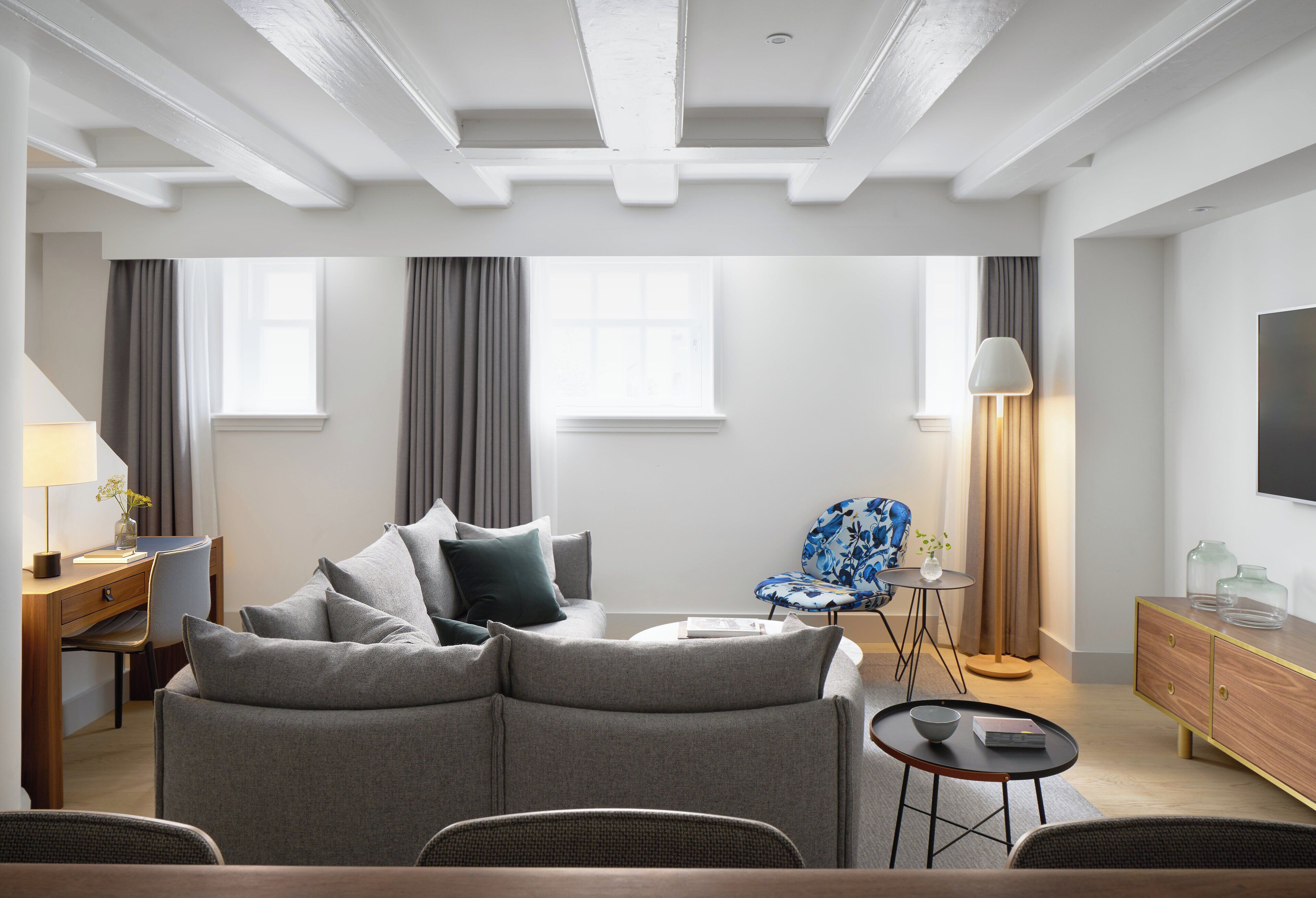 A modern living room with a sofa, a chair, a small table, and a lamp.