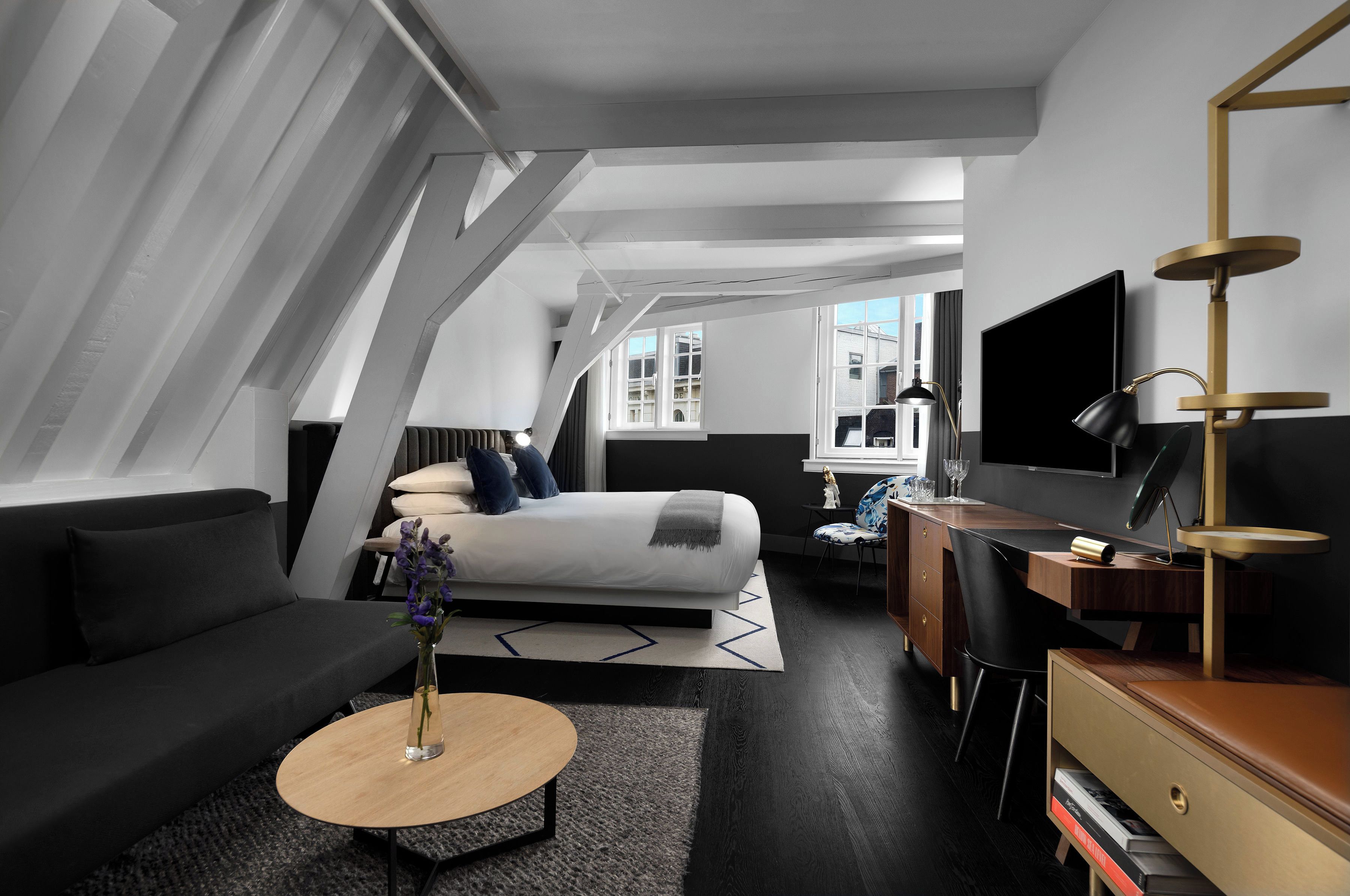 Ein modernes Hotelzimmer mit Bett, Schreibtisch, Fernseher und einer Sitzecke.