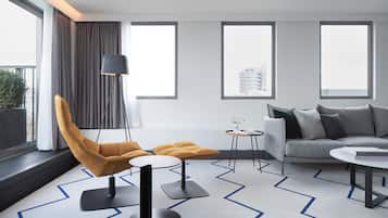 Una sala de estar moderna con un sofá, un sillón y un otoman, una mesita redonda y una lámpara de pie.