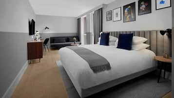 A modern hotel room with a large bed, a desk, and a seating area.