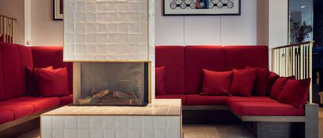 Una sala de estar moderna con un sofá rojo, una chimenea con azulejos blancos y una obra de arte abstracta enmarcada en la pared.