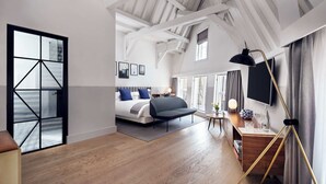 Una habitación de hotel moderna con una cama grande, un escritorio con lámpara y un televisor montado en la pared.
