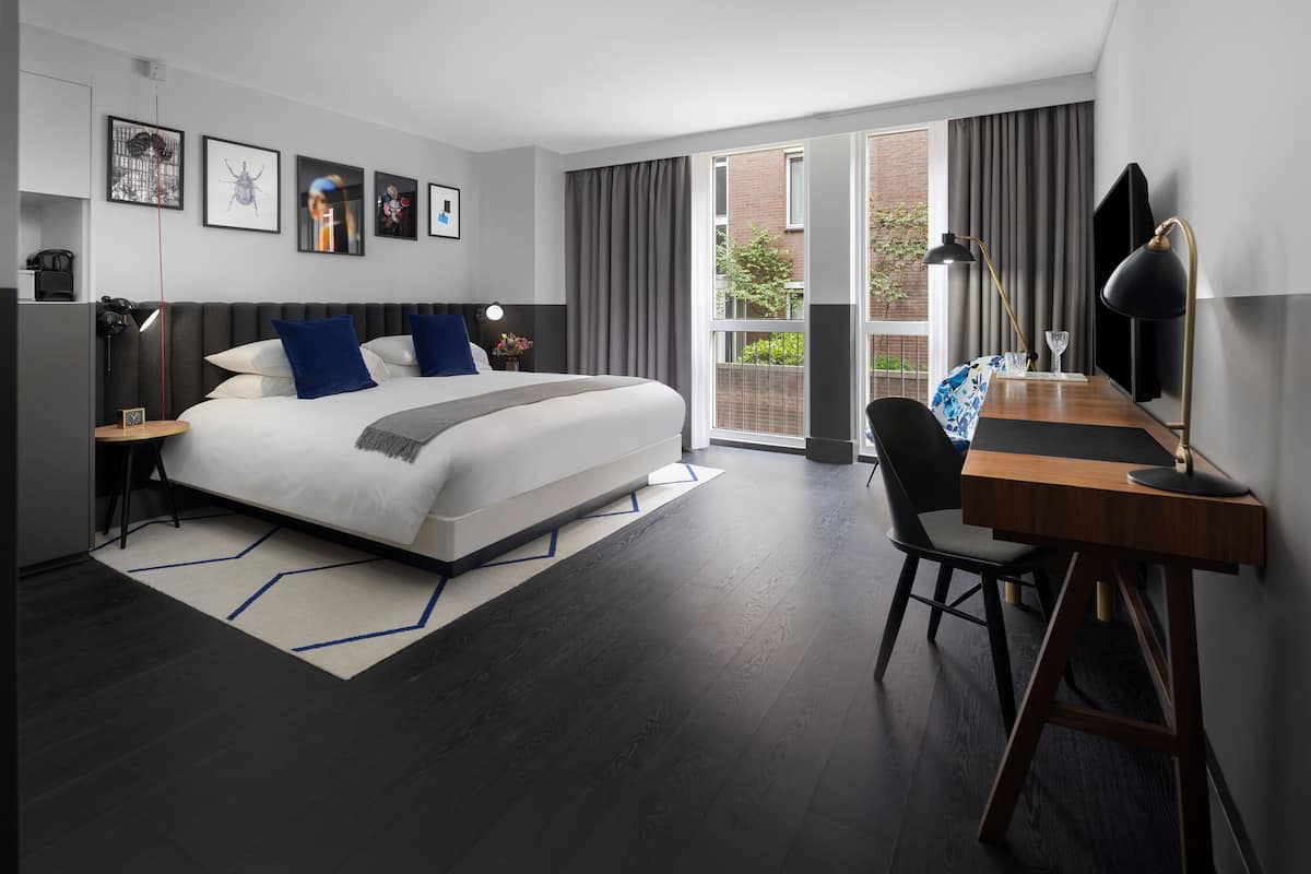 Ein modernes Hotelzimmer mit einem großen Bett, einem Schreibtisch und Blick ins Freie.