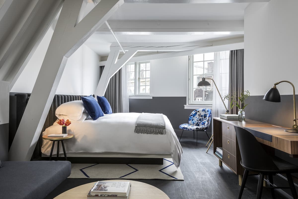 Ein modernes Schlafzimmer mit Bett, Schreibtisch und Stuhl, mit einem Fenster und Blick auf die Stadt.