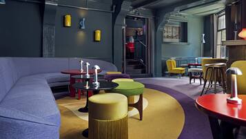 A modern interior with a curved sofa, round tables, and colorful ottomans.