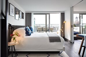 Relax in a stylish room with a large bed, a small table, and a view of the outdoor terrace through a large sliding door.