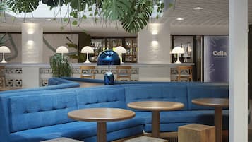 Een moderne lounge met blauwe zitplaatsen, ronde houten tafels en hangplanten.