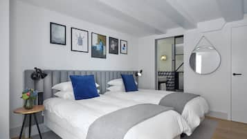 Un dormitorio moderno con dos camas, un espejo redondo y obras de arte en la pared.