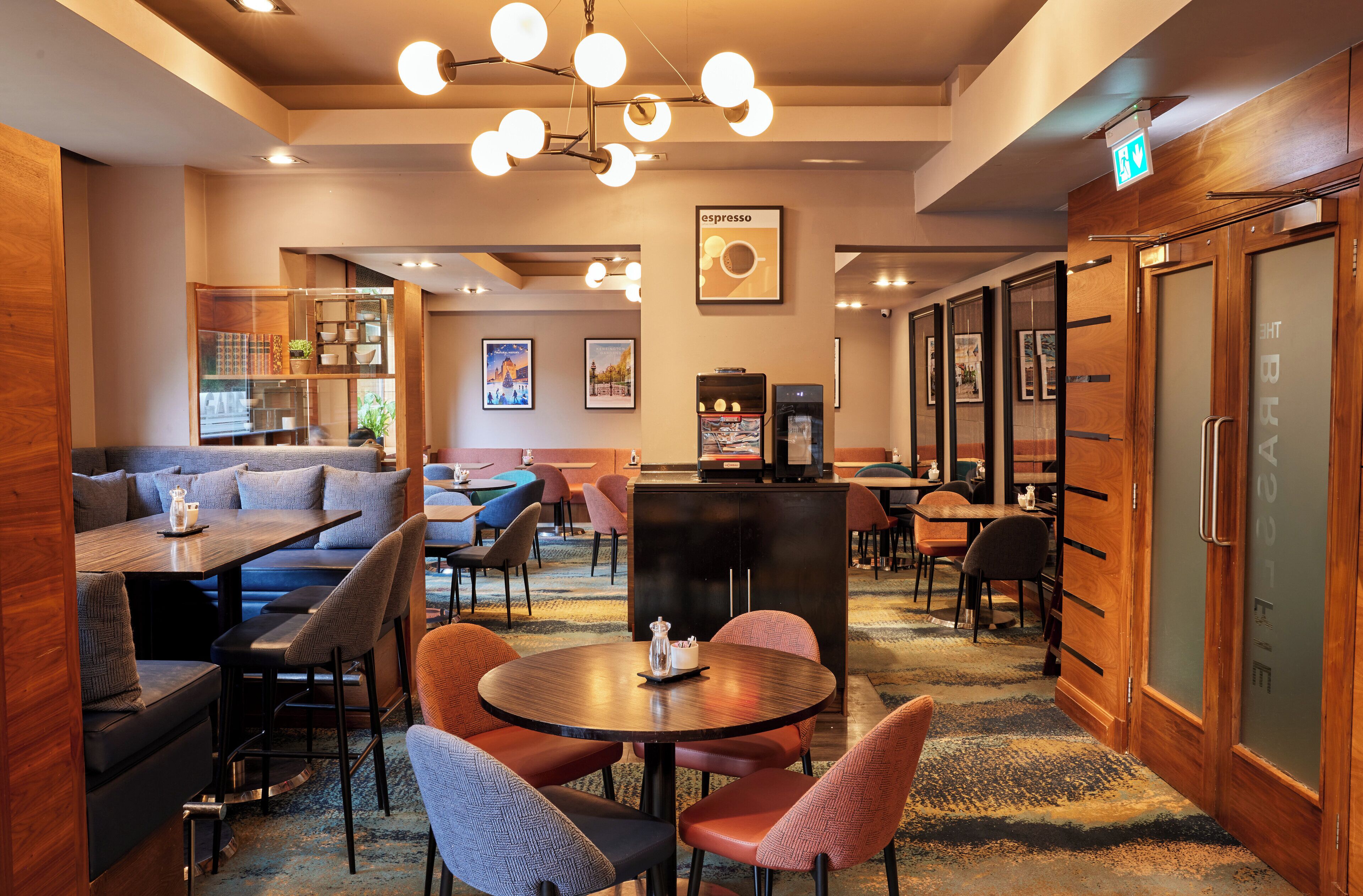 A hotel lobby with seating areas, a coffee machine, and a reception desk.