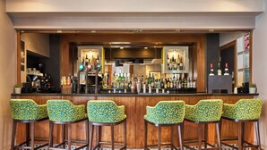 A bar area with wooden bar stools and a variety of bottles. - Thistle London Hyde Park Kensington Gardens (London)