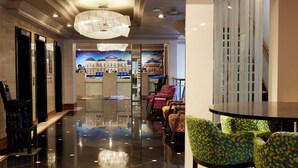 A lobby with a polished floor, a reception desk, and seating area with patterned chairs. - Thistle London Hyde Park Kensington Gardens (London)