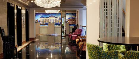 A lobby with a polished floor, a reception desk, and seating area with patterned chairs.
