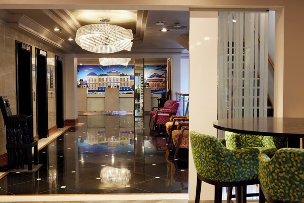 A lobby with a polished floor, a reception desk, and seating area with patterned chairs.