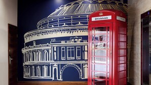A red telephone booth and a mural of a historical building. - Thistle London Hyde Park Kensington Gardens (London)