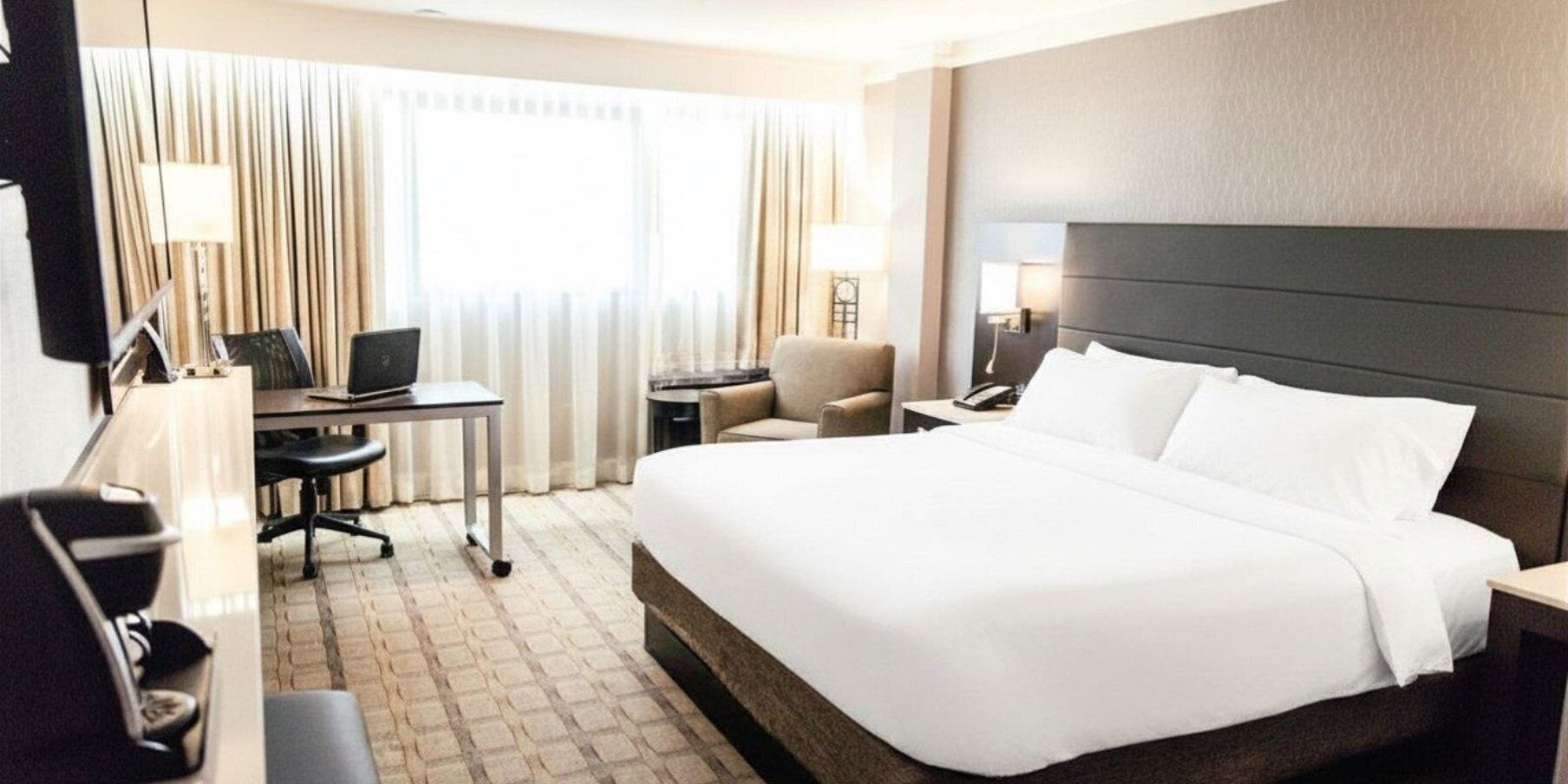 Hotellihuone, jossa on sänky, työpöytä, tuoli ja lamppu.
