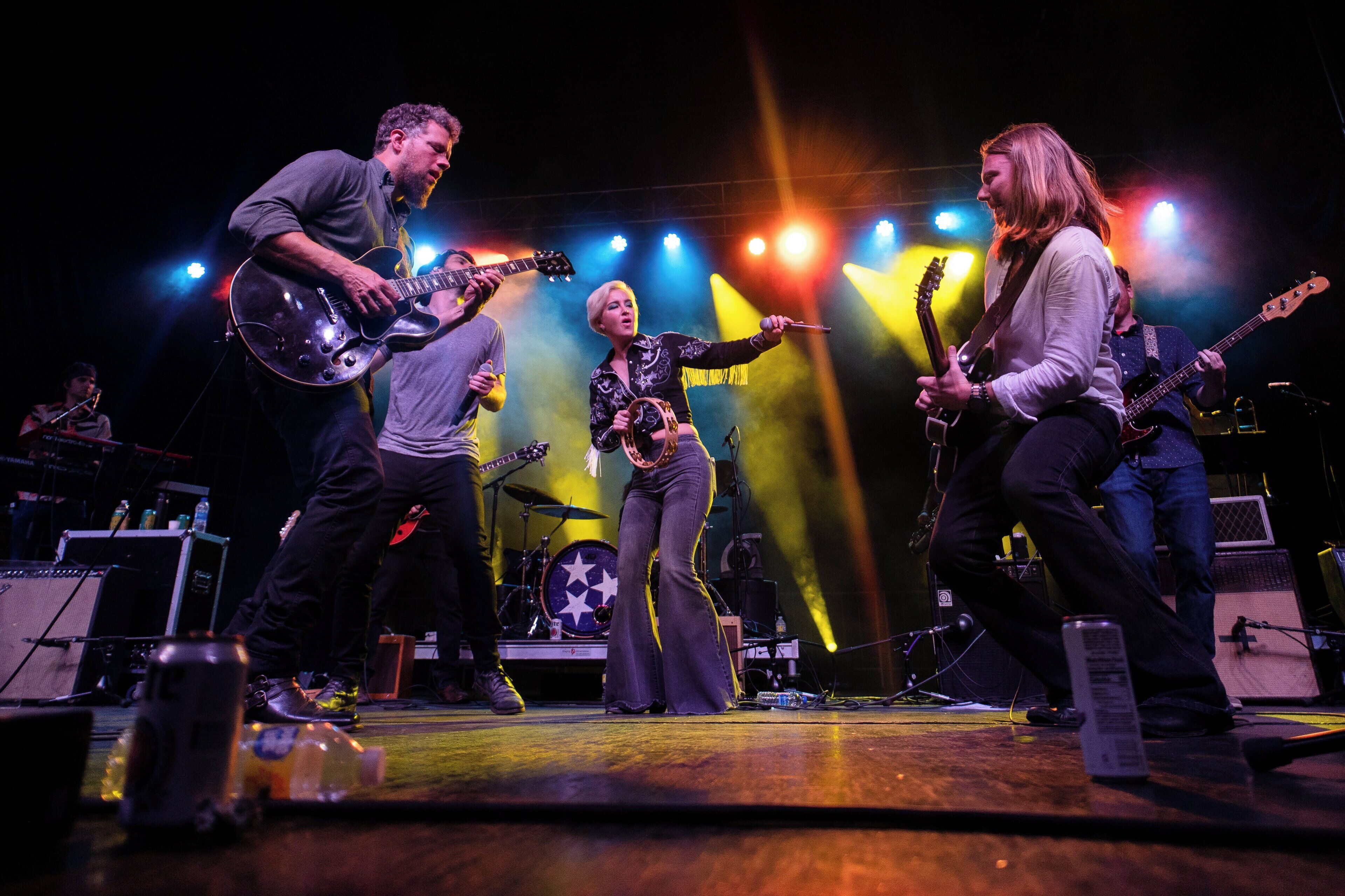 A band performing on a stage with musical instruments and a drum set.