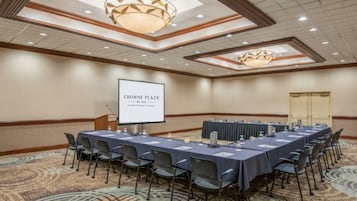 A conference room with a long table, chairs, a projector screen, and a carpeted floor.