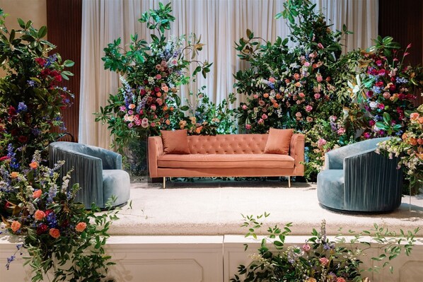 Relax in a comfortable seating area with plush sofa and chairs, surrounded by lush floral arrangements.