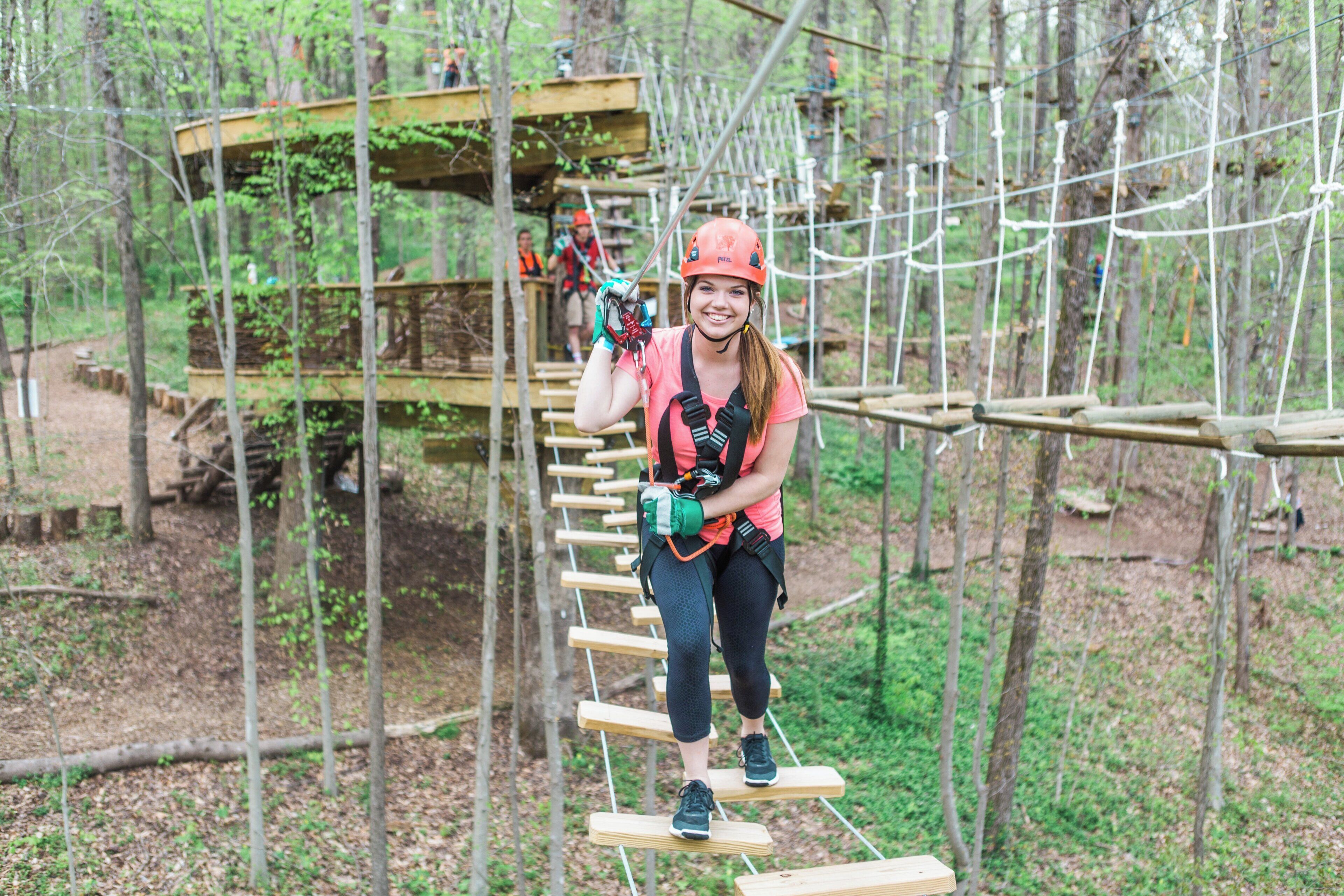 A person on a rope bridge in a forested area.