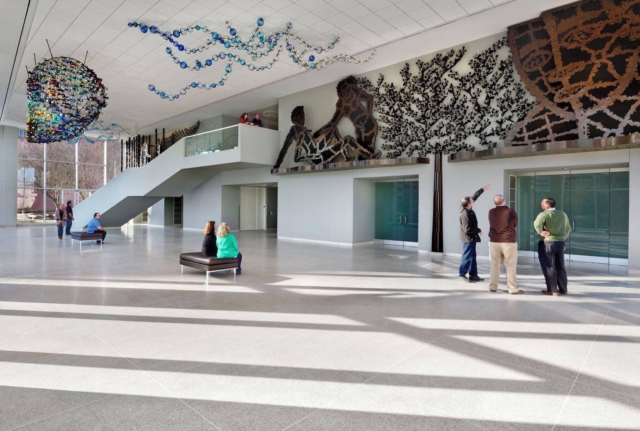 Un hall d’entrée spacieux avec un plafond haut, un escalier et une grande sculpture.