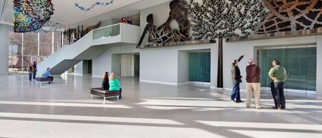Un hall d’entrée spacieux avec un plafond haut, un escalier et une grande sculpture.