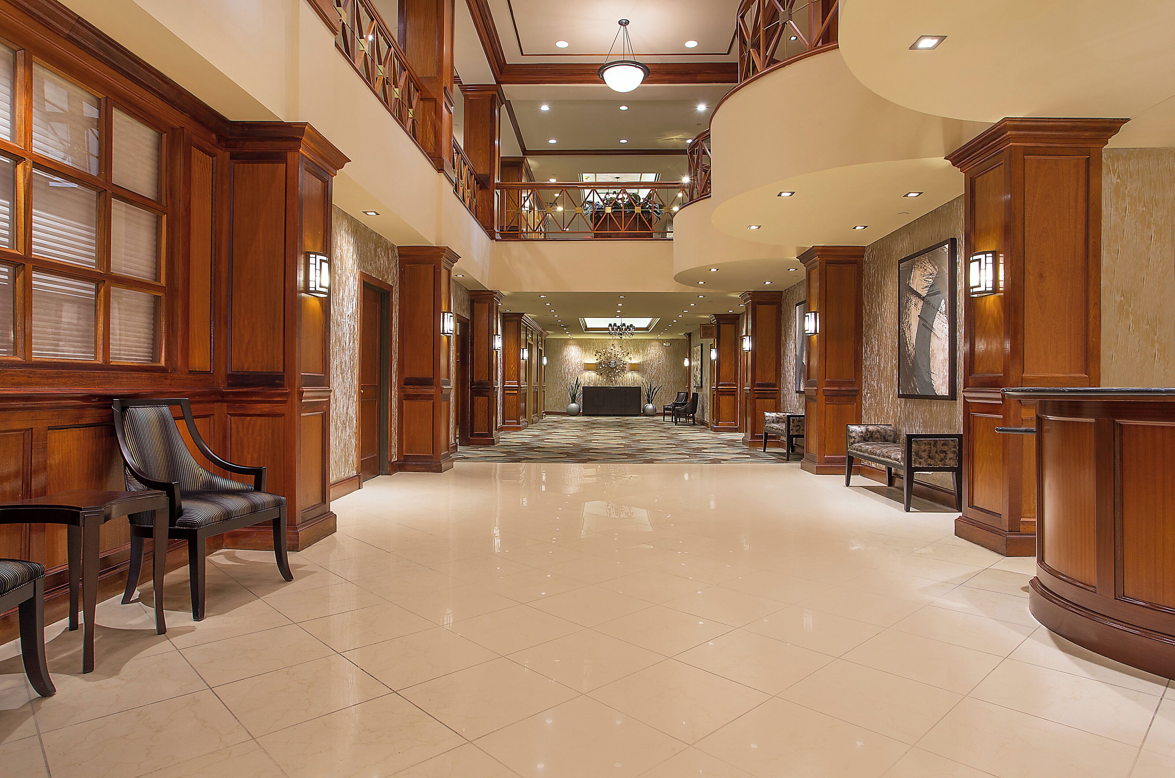 Eine geräumige Lobby mit hoher Decke, einer imposanten Treppe und einem Empfangstresen.