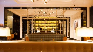A modern lobby with a bar area, seating, and a chandelier. - Blakemore Hyde Park (London)
