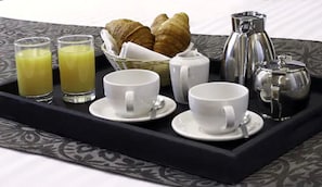 A tray with breakfast items including croissants, coffee pots, and glasses of orange juice.