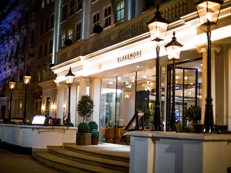 Entrada de un hotel con una fachada imponente, escalones que conducen a la entrada y un letrero que dice "Blakemore".