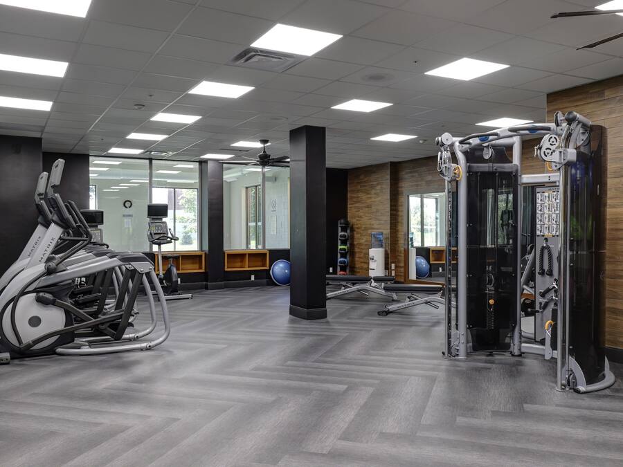 A gym with exercise equipment, a ceiling fan, and large windows.