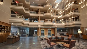 Un vestíbulo espacioso con techo alto, varios balcones y una zona de estar central con sofás y sillones.