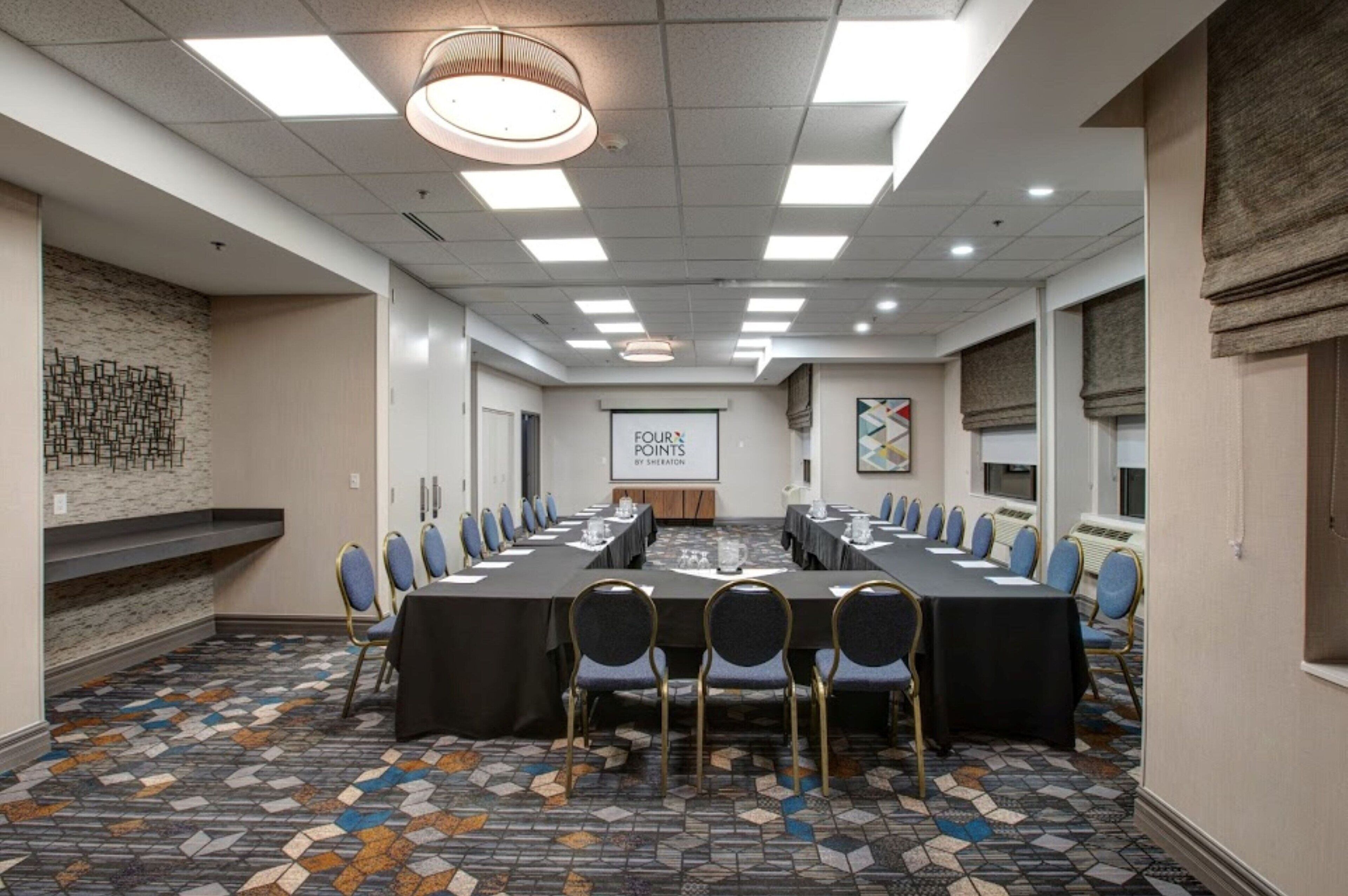 A conference room with a long table, chairs, and a projector screen.