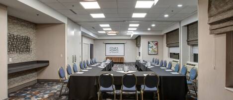A conference room with a long table, chairs, and a projector screen.