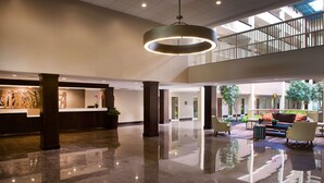 A spacious lobby with a reception desk, seating area, and a high ceiling with a circular light fixture.