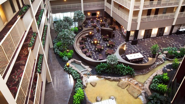 A multi-level atrium with outdoor seating areas, a water feature, and balconies.