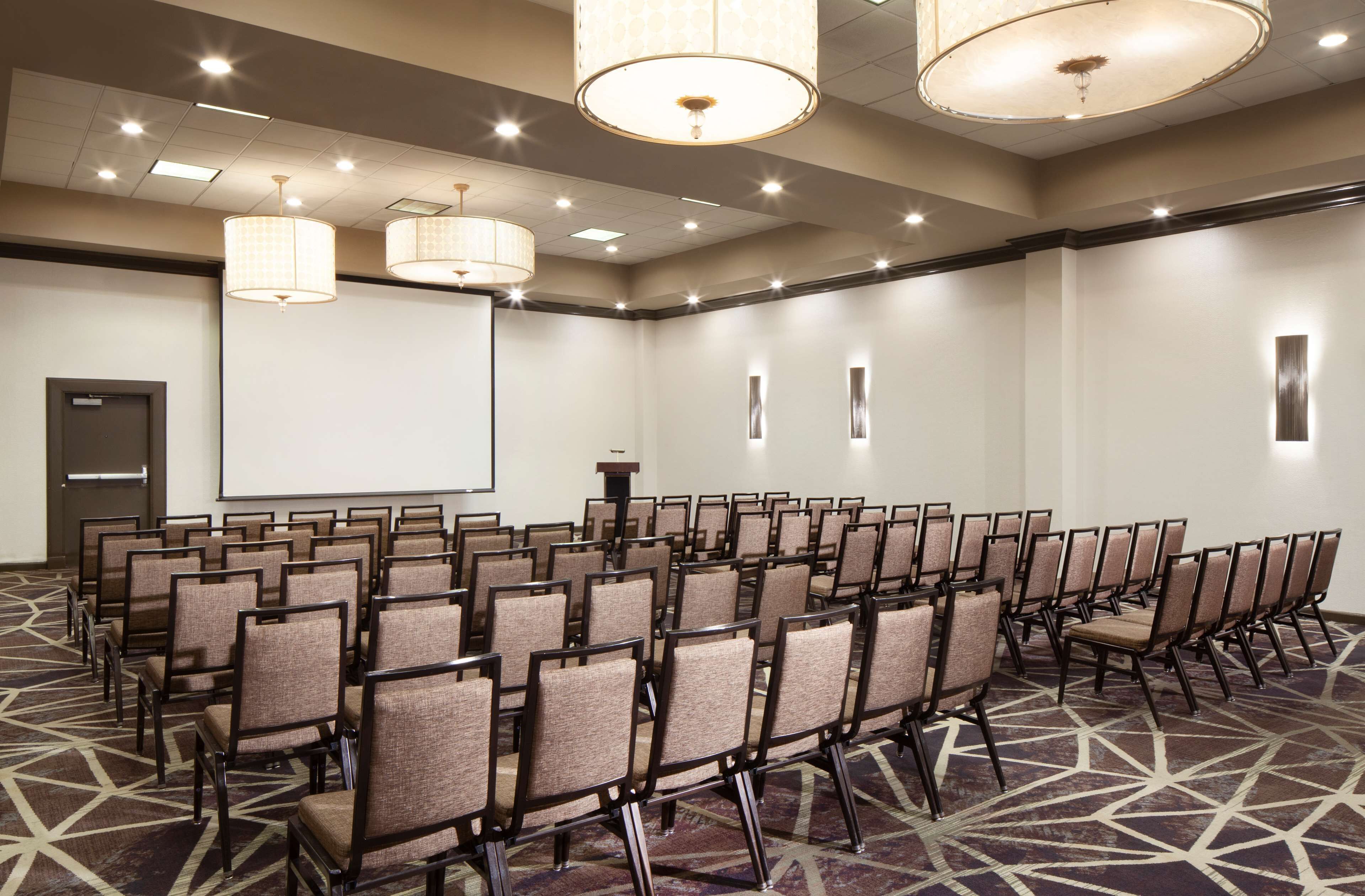 A conference room with rows of chairs, a projector screen, and a podium.