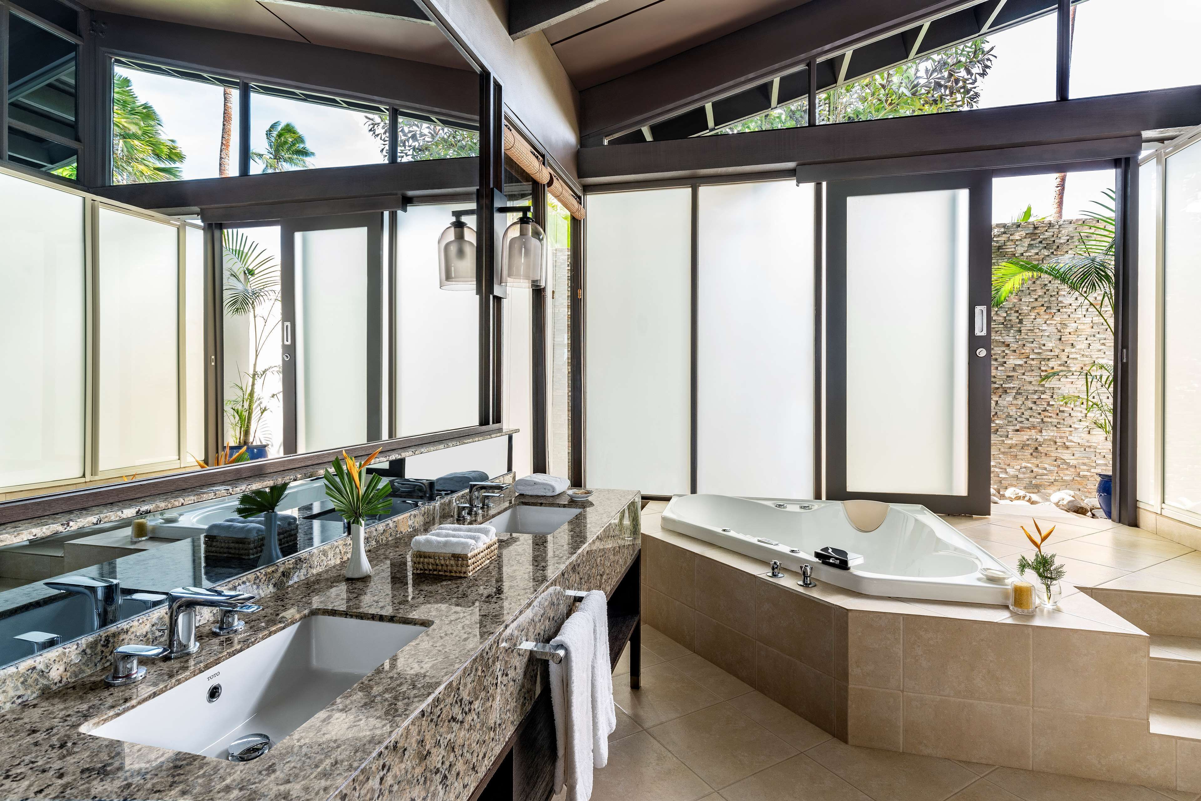 Un baño moderno con un lavamanos grande, una bañera independiente y un espejo amplio.