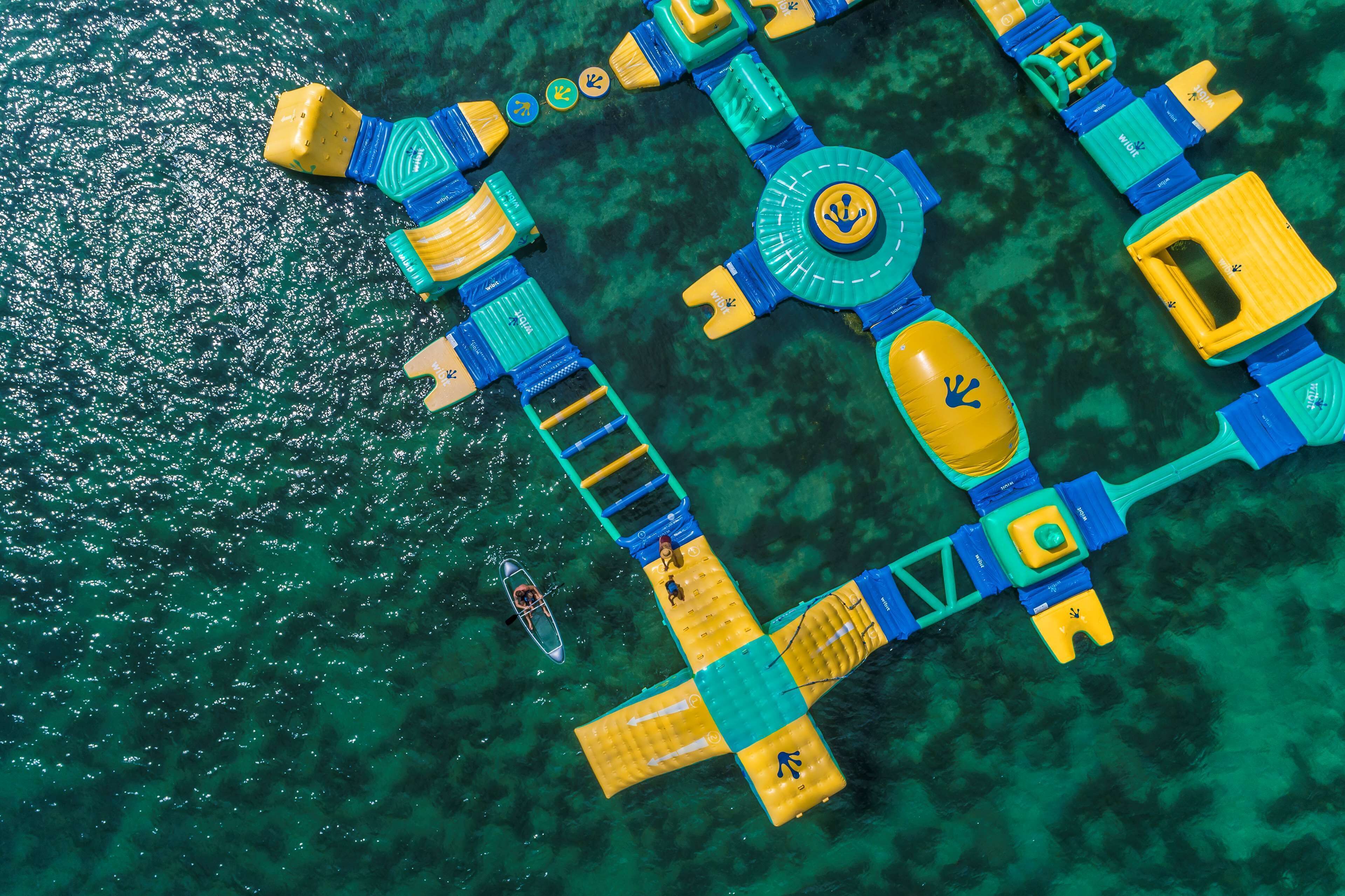An aerial view of a floating structure with multiple interconnected platforms, a central circular area, and a small boat nearby.