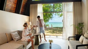 A room with a sofa, a coffee table, and a view of the beach. - Shangri-La Yanuca Island, Fiji (Yanuca Island)