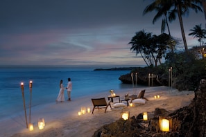 A beach setting with a couple walking, beach chairs, and lanterns. - Shangri-La Yanuca Island, Fiji (Yanuca Island)